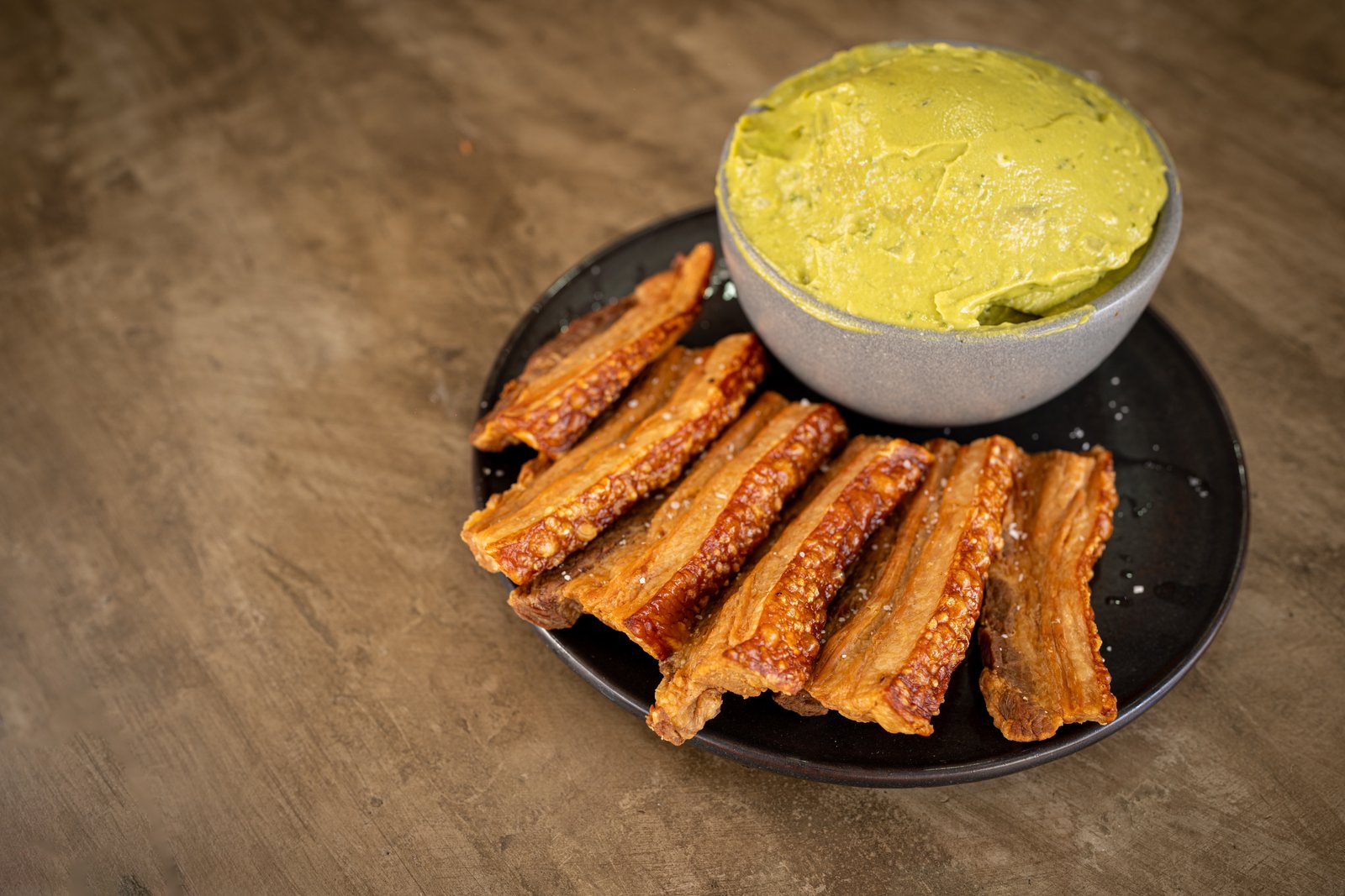 Chicharrón de pork belly servido con guacamole