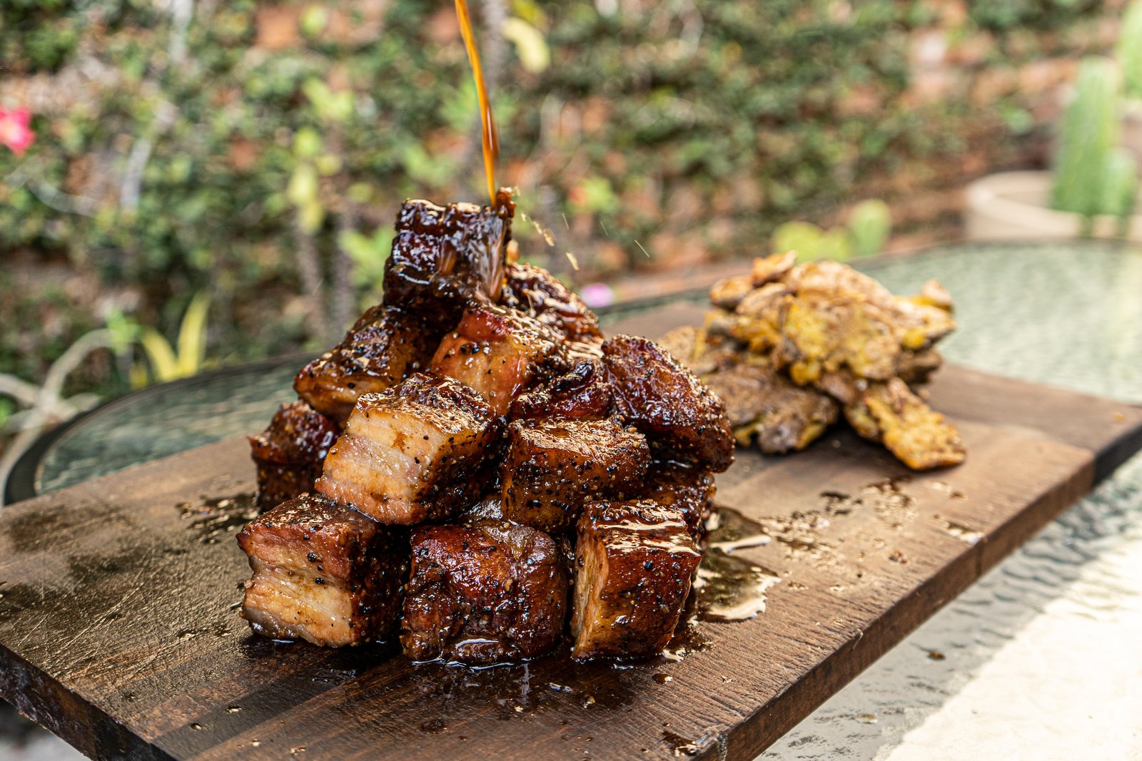 Burnt ends de pork belly glaseados, servidos con papitas al horno