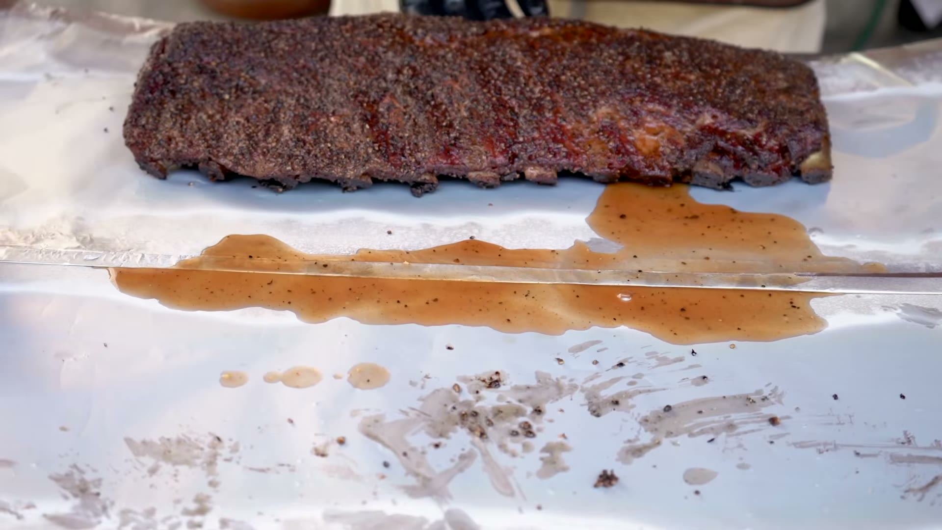 Costillas en el ahumador mientras se prepara la salsa BBQ